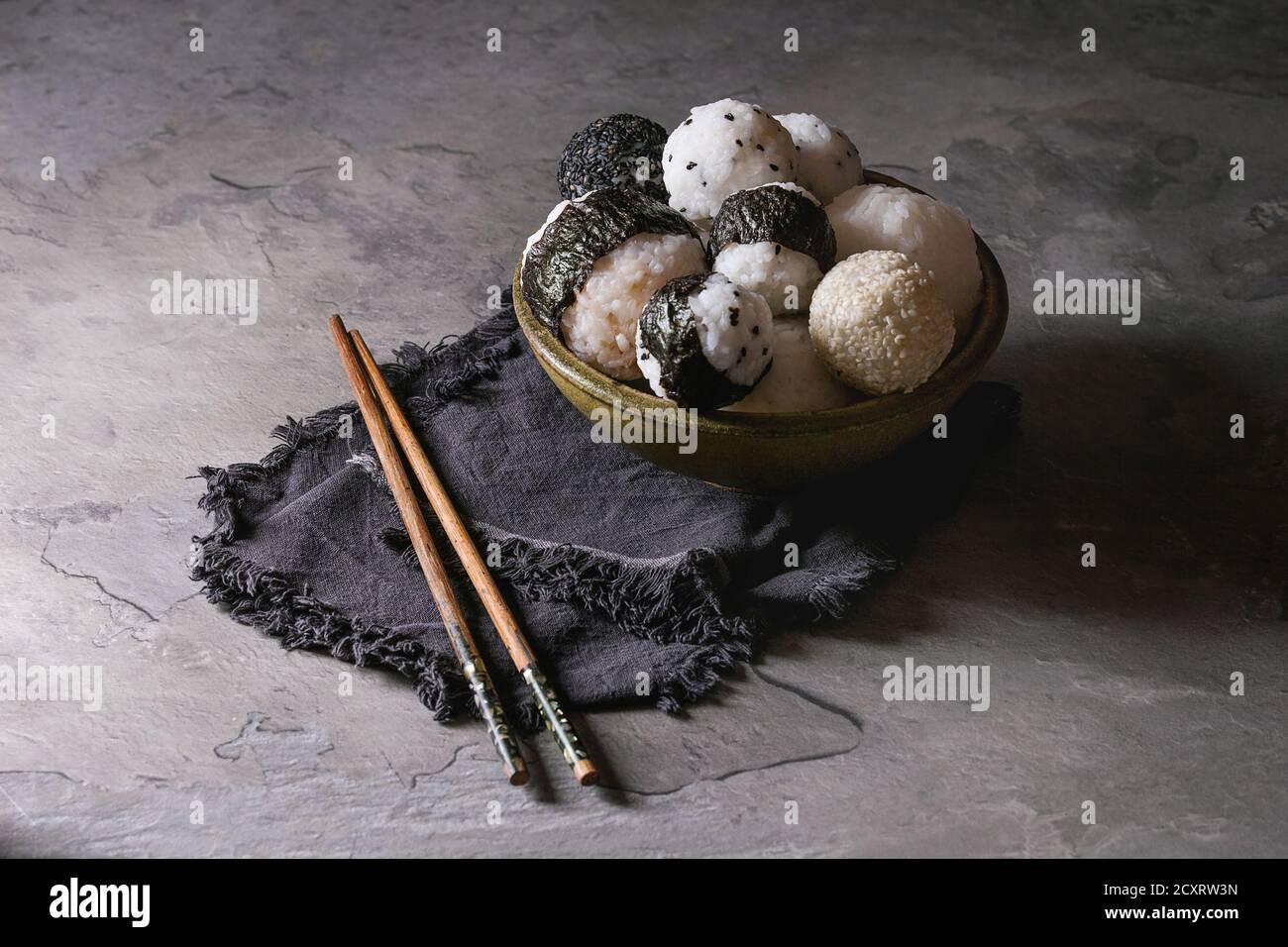 Bol avec différentes tailles de boules de riz et sésame noir avec des Algues Nori, servi avec des œufs durs, de la sauce de soja, des baguettes sur le tableau gris. Asian sty Banque D'Images