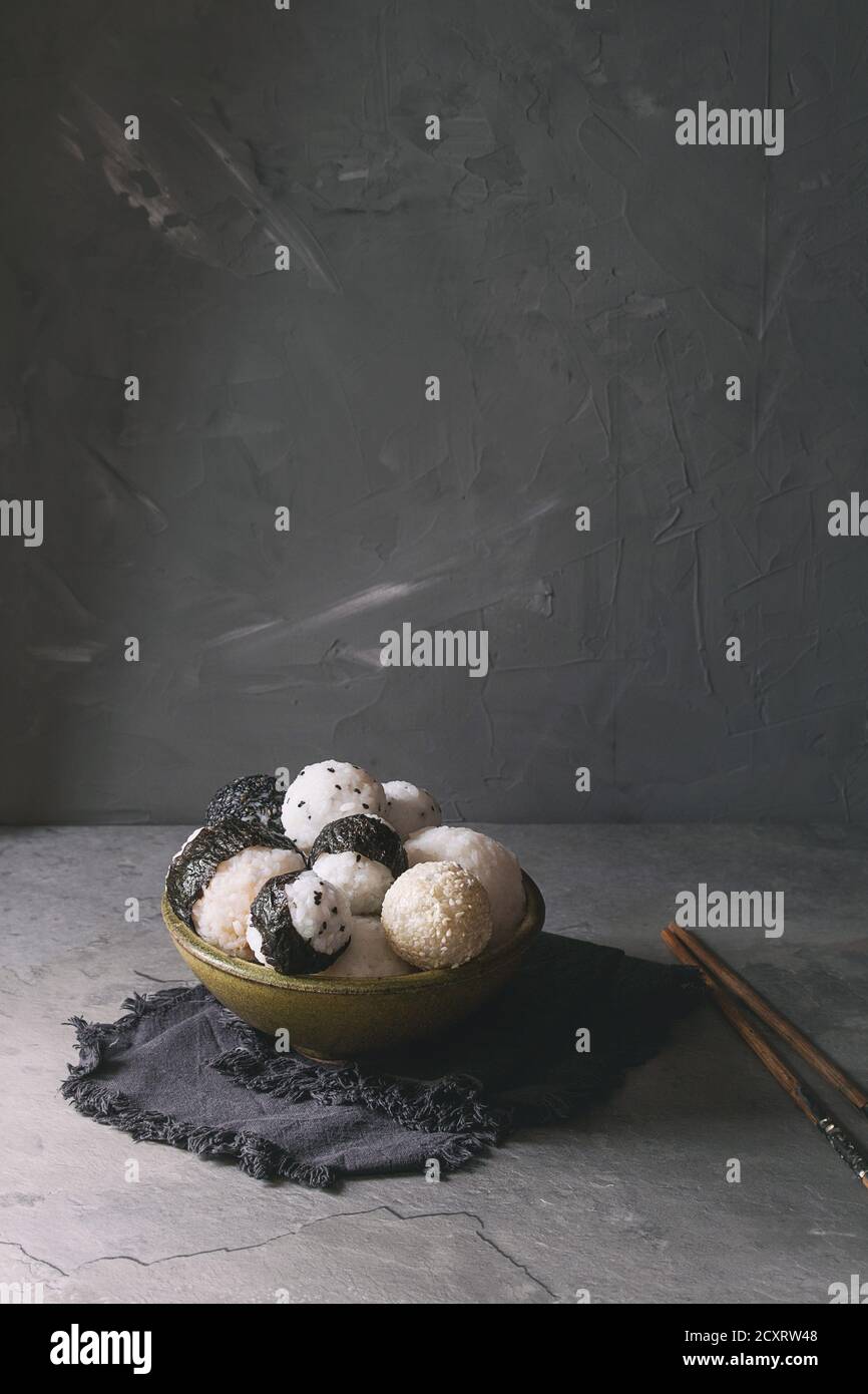 Bol avec différentes tailles de boules de riz et sésame noir avec des Algues Nori, servi avec des œufs durs, de la sauce de soja, des baguettes sur le tableau gris. Asian sty Banque D'Images