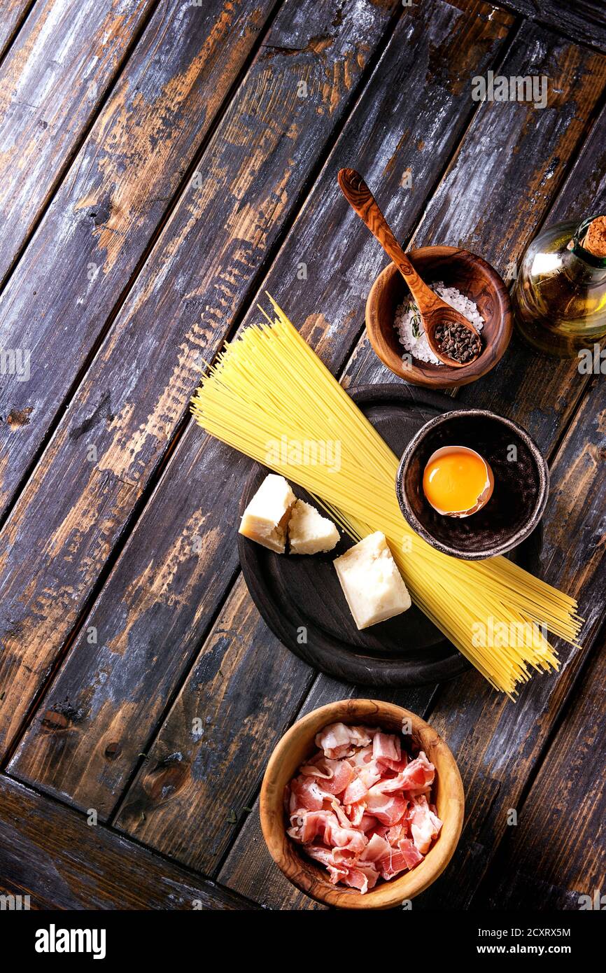 Ingrédients pour la cuisine italienne traditionnelle Pasta alla carbonara. Spaghettis non cuits, la pancetta bacon, fromage parmesan, d'oeuf, sel, poivre en bois d'bo Banque D'Images