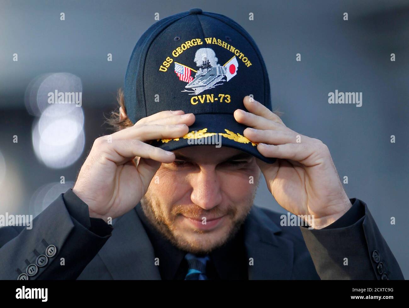 L'acteur Taylor Kitsch porte une casquette lors d'une conférence de presse  pour promouvoir son film « Battleship » au-dessus d'un pont de vol du porte- avions USS George Washington au port de Yokosuka,
