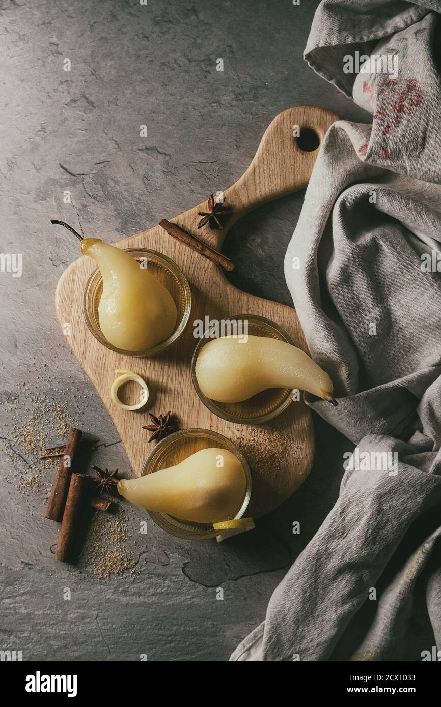 Dessert traditionnel confit de poires au vin blanc servi dans des bols en verre avec le sirop et les zestes de citron sur le bord en bois servant plus de texture gris table. Top v Banque D'Images