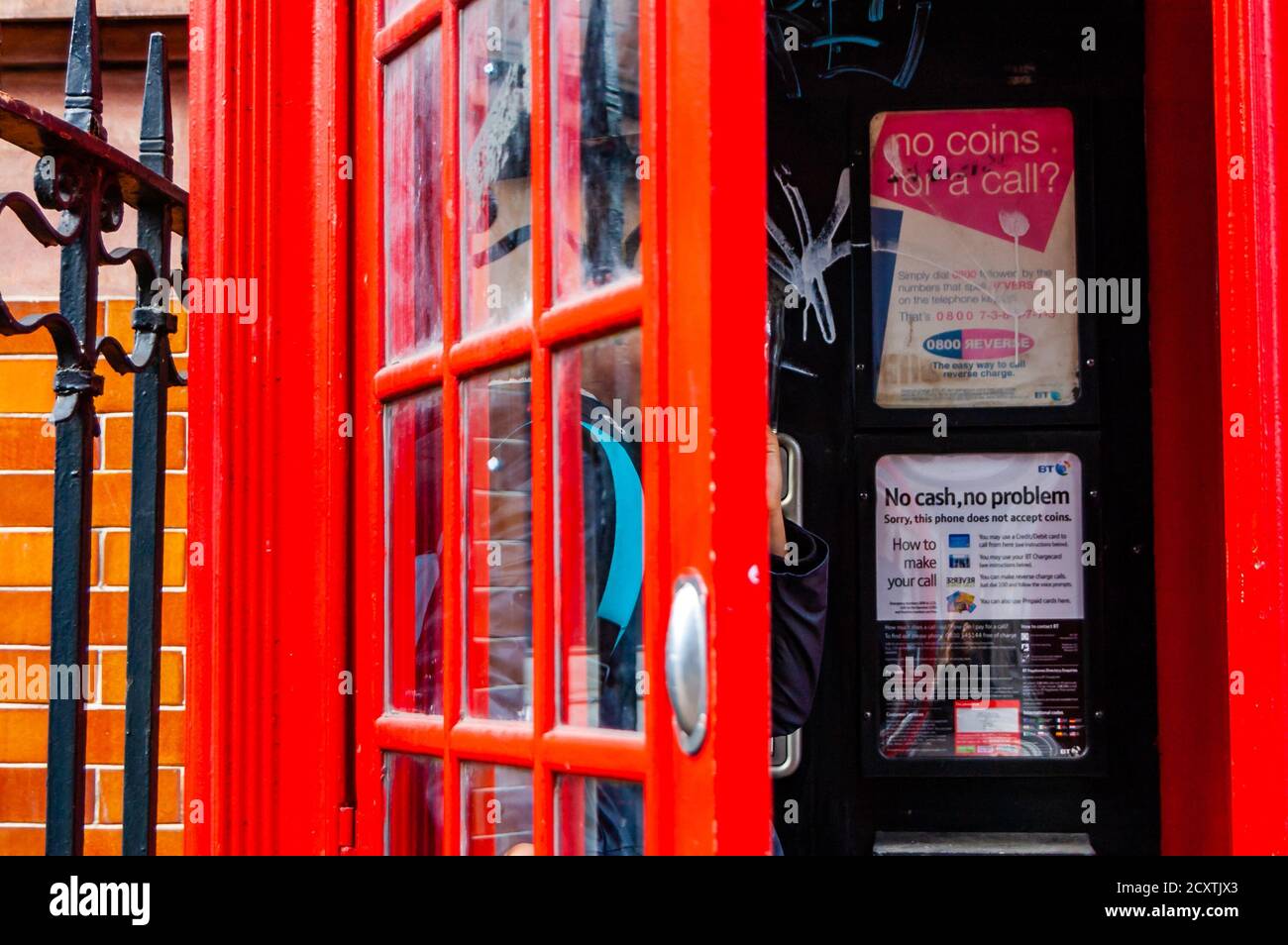 Londres, Royaume-Uni - 14 septembre 2017 : célèbre boîte téléphonique rouge avec une personne à l'intérieur. Informations utiles sur les appels à l'intérieur de la boîte. Banque D'Images