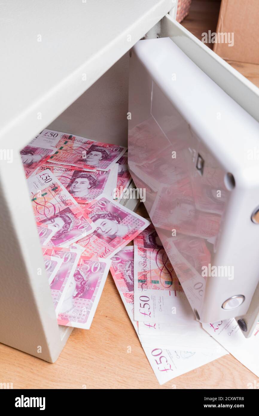 Coffre-fort domestique assis sur les planchers et débordant avec des billets de cinquante livres britanniques. Banque D'Images