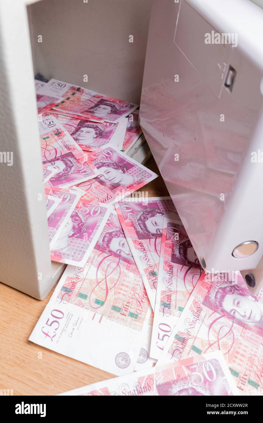 Coffre-fort domestique assis sur les planchers et débordant avec des billets de cinquante livres britanniques. Banque D'Images