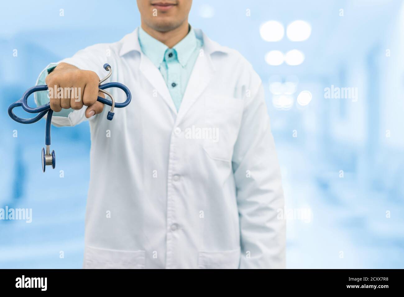 Médecin homme tenant un stéthoscope, souriant sur le fond de l'hôpital. Service de santé, pratique générale et concept de carrière médicale. Banque D'Images