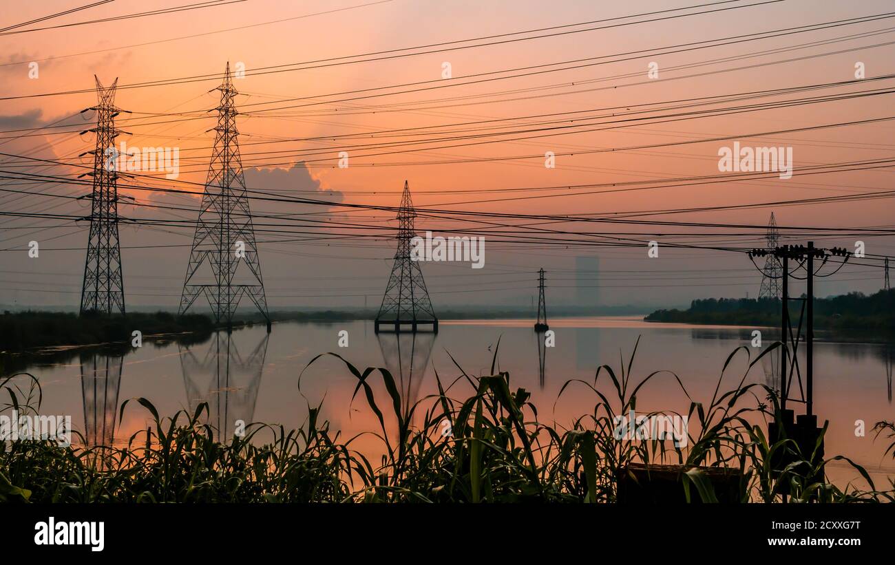 Lignes électriques haute tension à Sunrise/Sunset. Station de distribution d'électricité.Saltpans à Mumbai. Banque D'Images