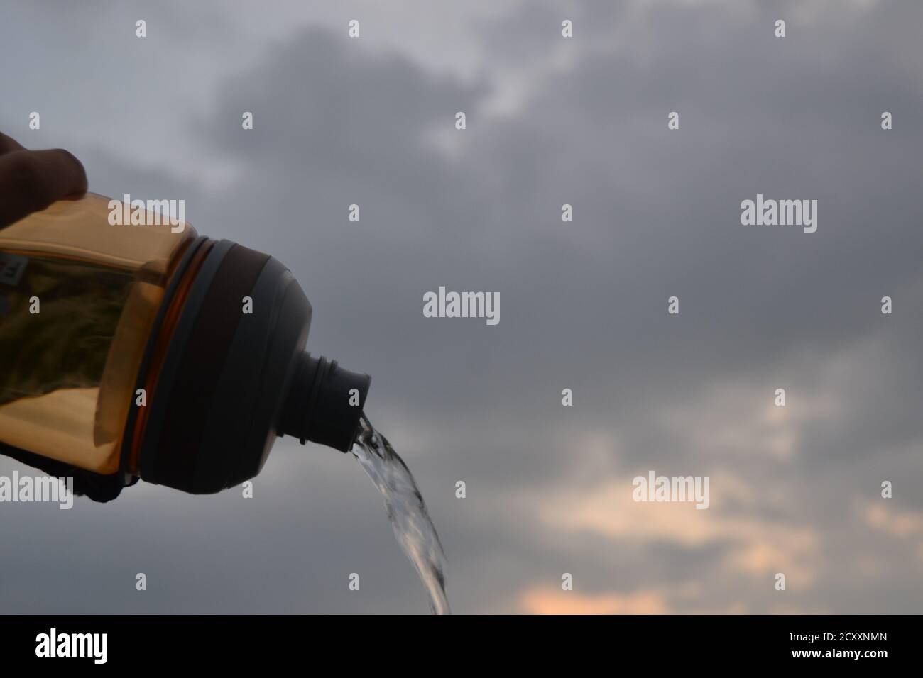 Bouteille d'eau avec ciel nuageux en arrière-plan. Banque D'Images