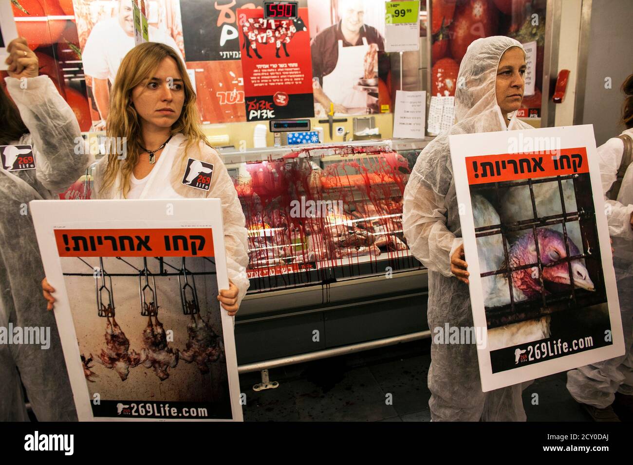 Activists calling for animal rights hold placards as they stand in front of  meat displayed in refrigerators, which the protesters covered in mock  blood, at a supermarket in Tel Aviv November 7,