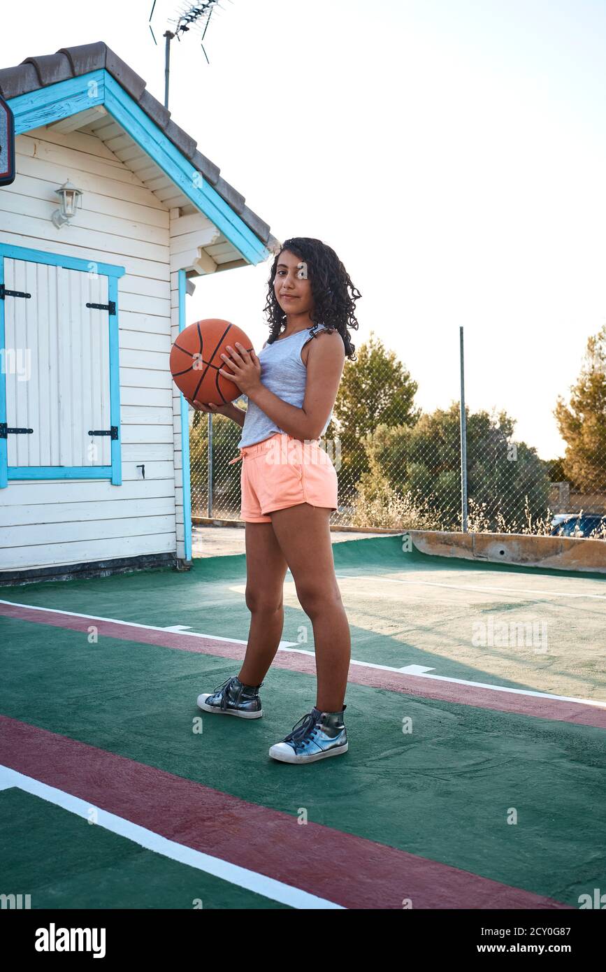 Une fille debout sur un terrain de basket-ball posant pour un appareil photo. Concept de style de vie Banque D'Images