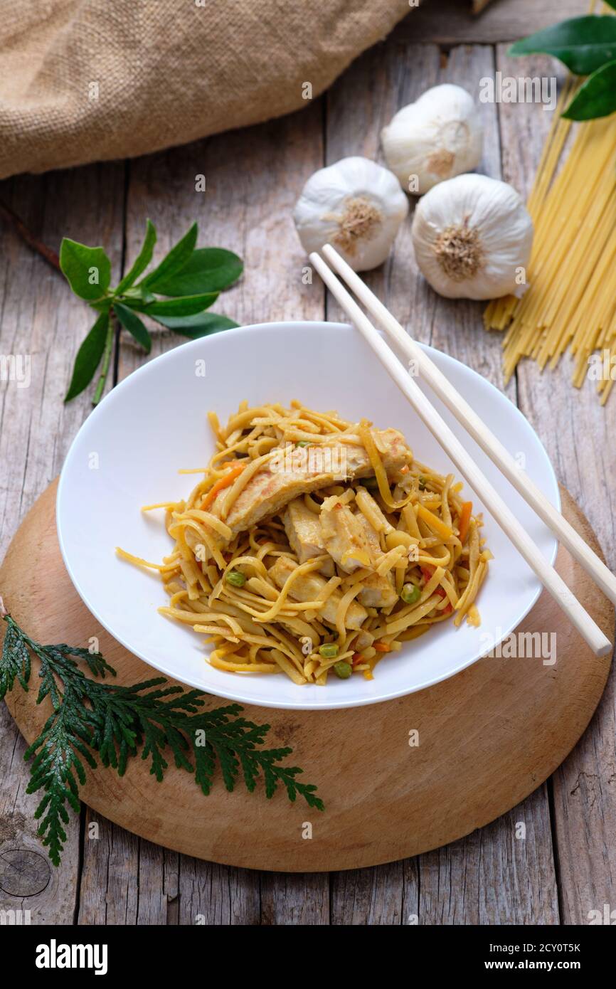 Cuisine asiatique - nouilles de Bami goreng sur fond rustique et baguettes Banque D'Images