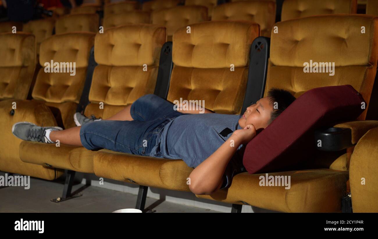 Un garçon posé sur le fauteuil et regarder un film au cinéma. Banque D'Images