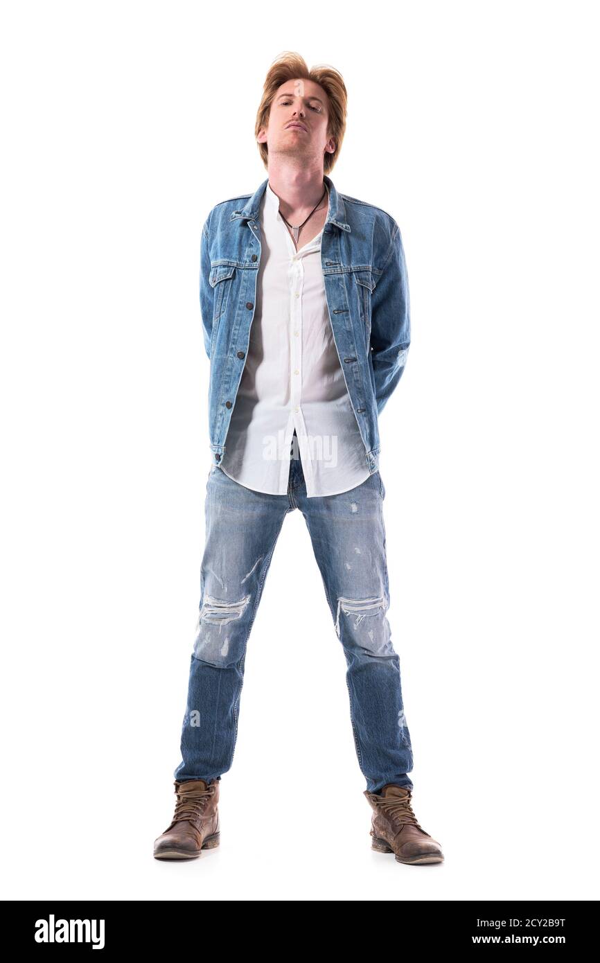 Jeune rebelle coq jeune homme beau en Jean regardant l'appareil photo avec la tête en arrière. Corps entier isolé sur fond blanc. Banque D'Images