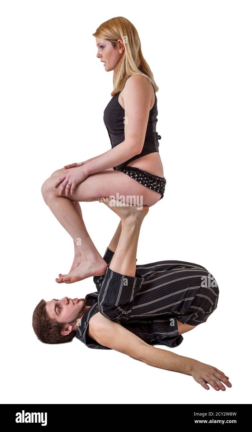 Jeune couple avec équilibre acrobatique pratiques femme assise sur l'homme s upstretched les jambes. Banque D'Images