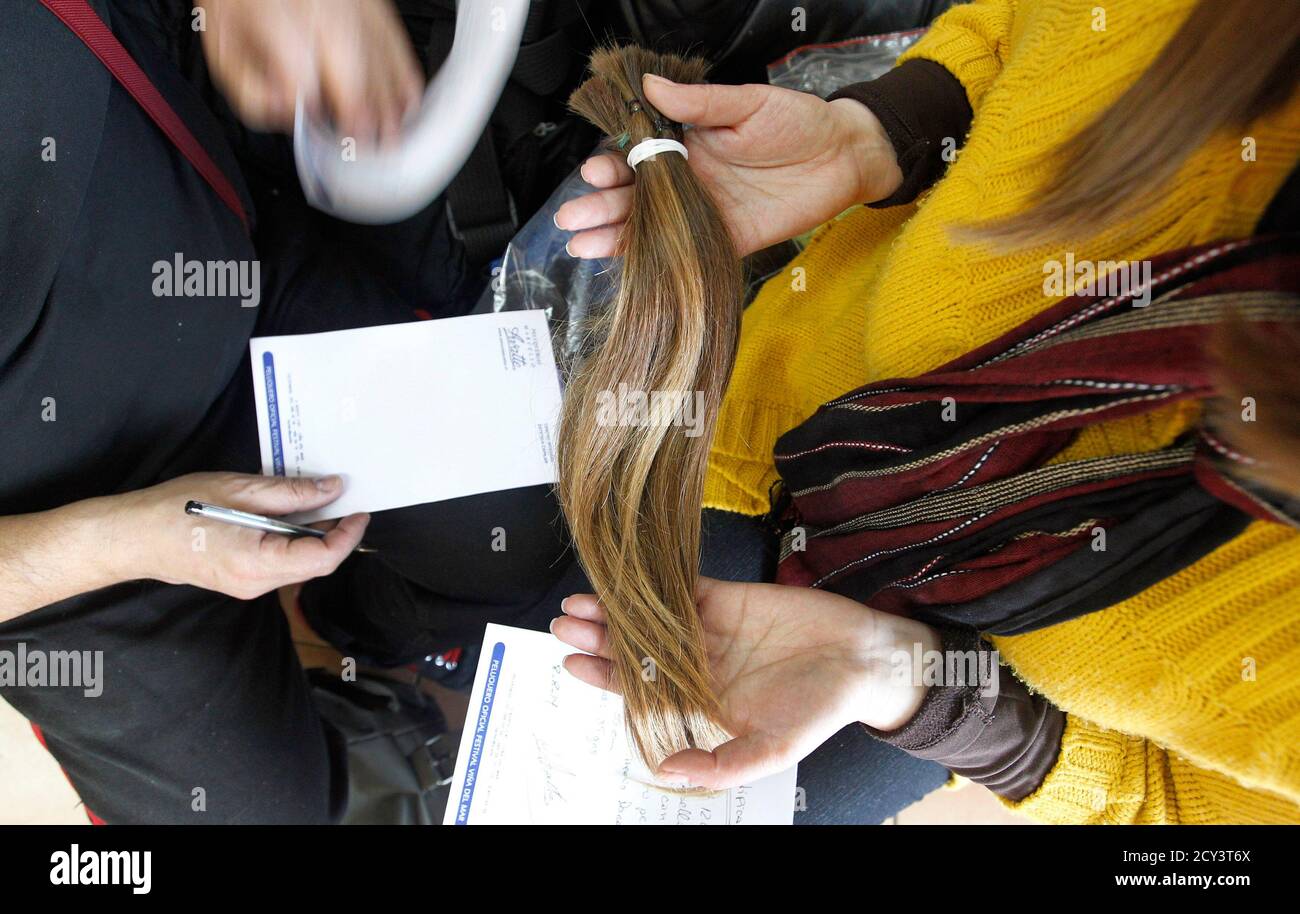 Pamela Matus (R) holds locks of her hair as stylist Marcelo Avatte (L) writes down the characteristics, for the making of a natural hair wig for a girl undergoing chemotherapy for cancer, Pamela Matus (R) holds locks of her hair as stylist Marcelo Avatte (L) writes down the characteristics, for the making of a natural hair wig for a girl undergoing chemotherapy for cancer,