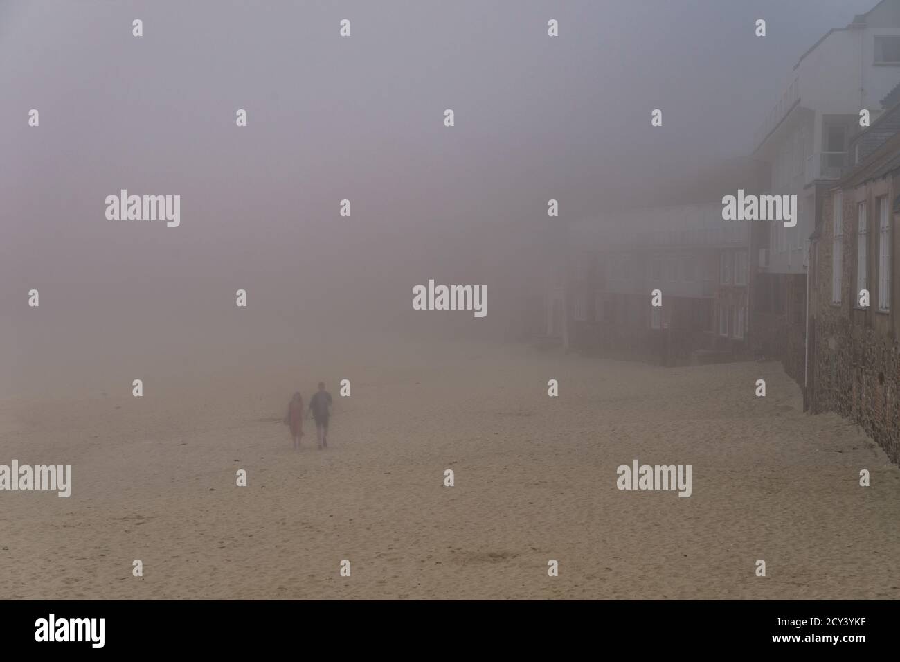 Couple marchant dans la brume sur la plage St Ives Cornwall ROYAUME-UNI Banque D'Images