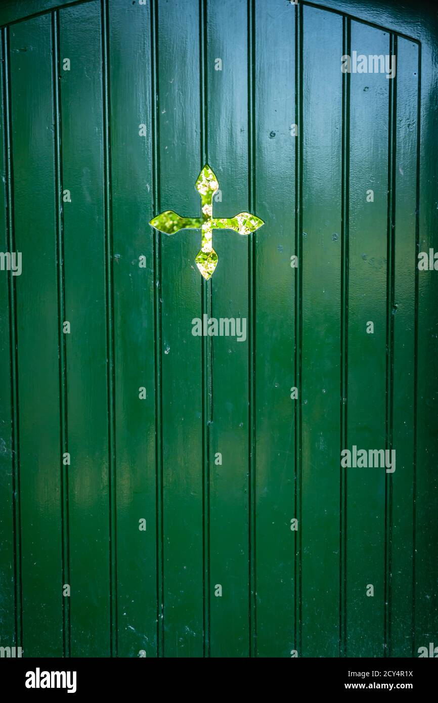 Porte en bois peint dans le mur de jardin avec découpe en forme de croix Banque D'Images