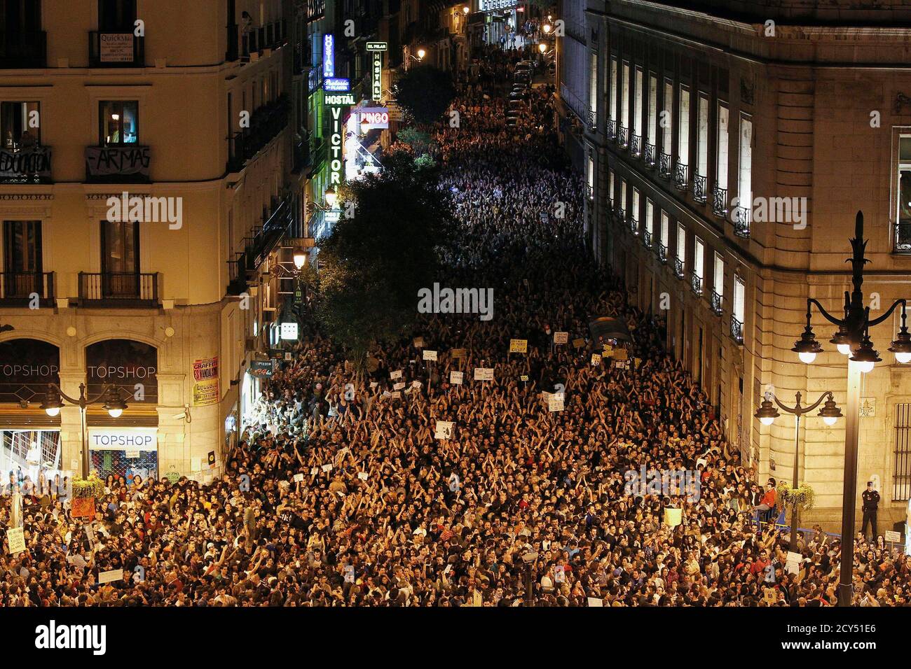 Demonstrators raise their arms just after midnight as they fill up Madrid's  Puerta del Sol, spilling into sidestreets early May 21, 2011. Tens of  thousands of Spaniards angry over joblessness protested for