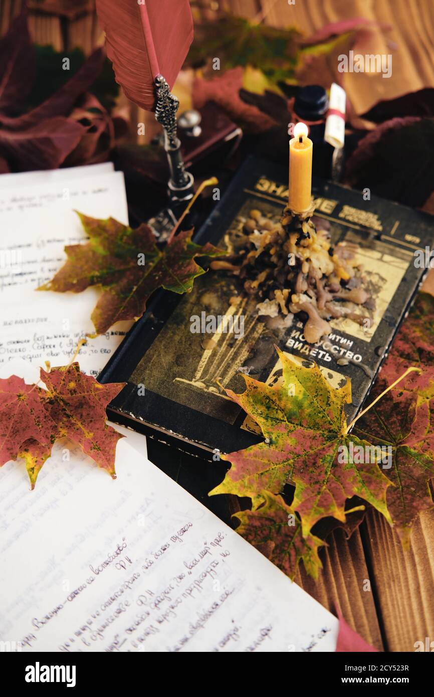 Photo verticale d'une bougie et de feuilles d'automne sur un livre Banque D'Images