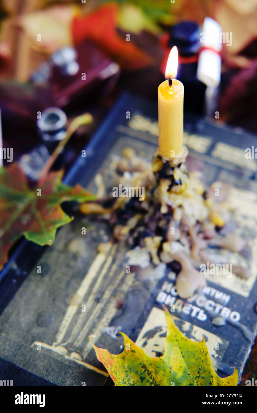 Photo verticale d'une bougie et de feuilles d'automne sur un livre Banque D'Images