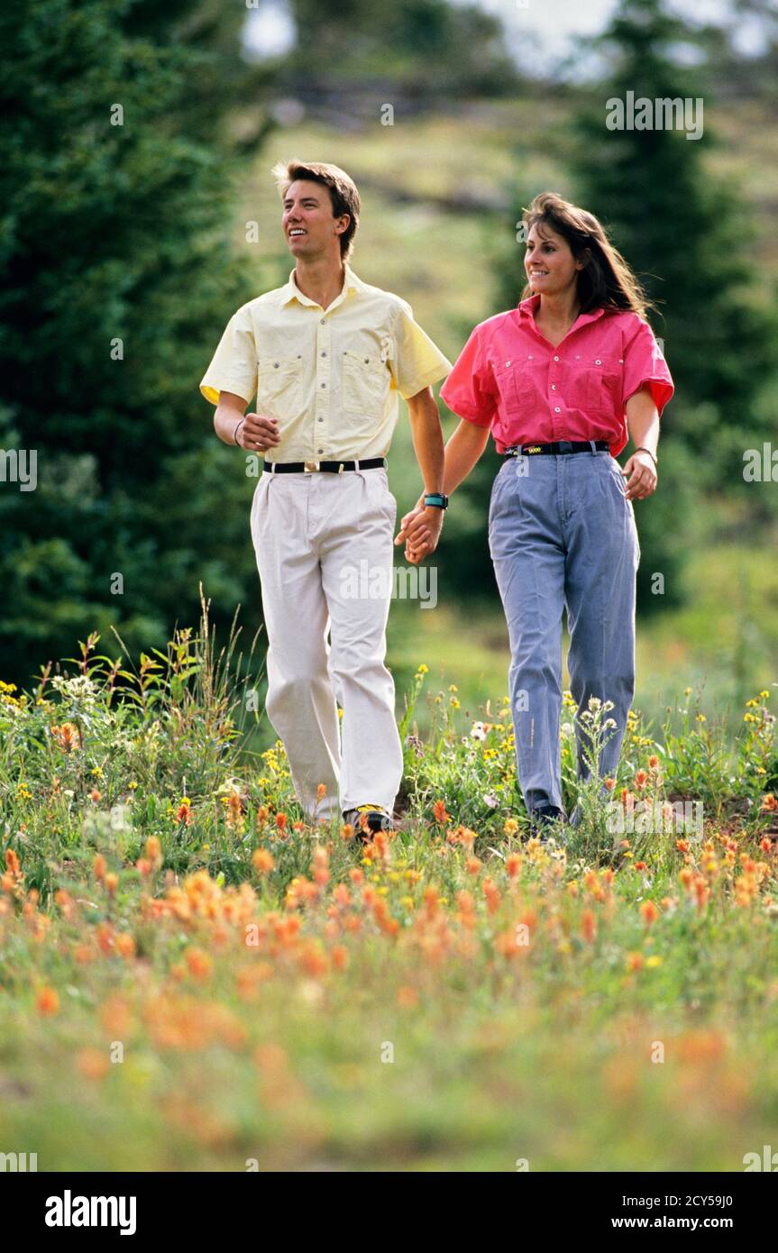 ANNEES 1990 HOMME ET FEMME COUPLE TENANT LES MAINS PORTANT DES VETEMENTS DECONTRACTES PROMENADE DANS LE PASSE DU SANCTUAIRE PRES DE VAIL COLORADO USA KS29626 WAL004 HARS HISTOIRE DE VETEMENTS ROMANCE