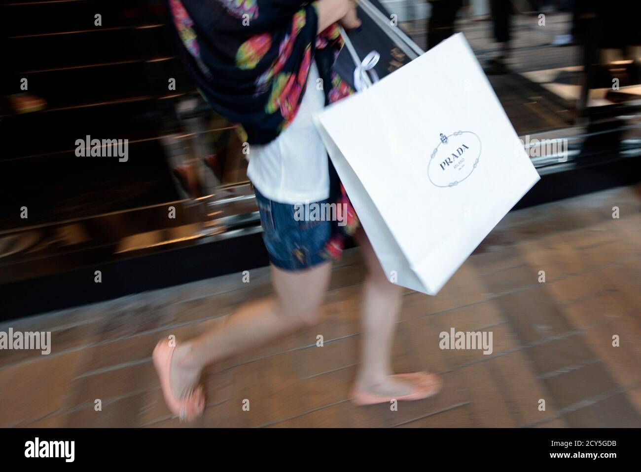 A mainland Chinese visitor with a Prada shopping bag walks outside a Prada  store at Hong Kong's Tsim Sha Tsui shopping district June 23, 2011. Italian  fashion house Prada SpA said on