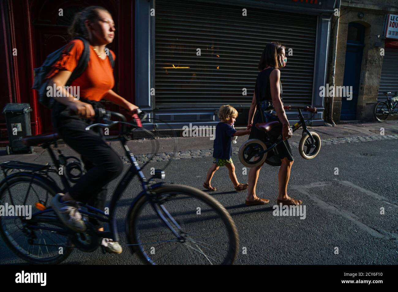 Bordeaux - 08/27/2020: Une fille à vélo passe devant une mère avec un bycicle et un enfant à la main dans les rues Banque D'Images
