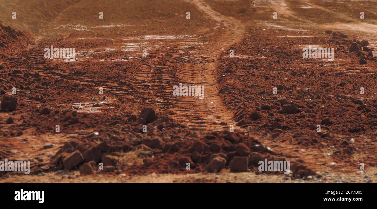 Grande image d'une route rouge sablonneuse poussiéreuse avec des traces de pneus sur elle ressemblant à la planète Mars. Mise au point sélective sur le centre de l'image. Banque D'Images