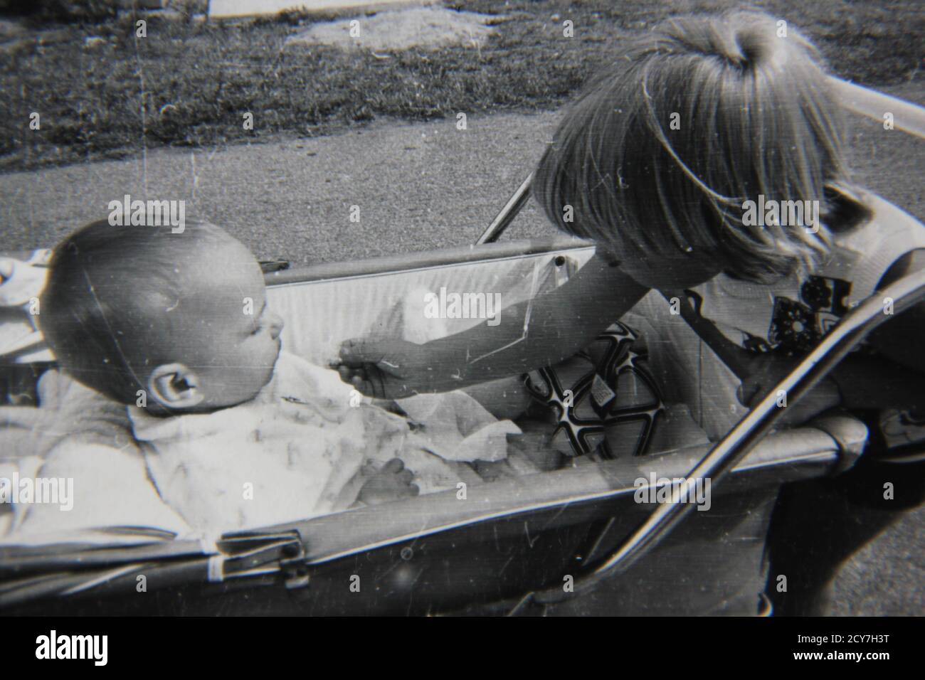 Belle Photographie Vintage En Noir Et Blanc Des Annees 1970 D Une Fille Jouant Avec Un Petit Bebe Assis Dans Une Poussette Photo Stock Alamy