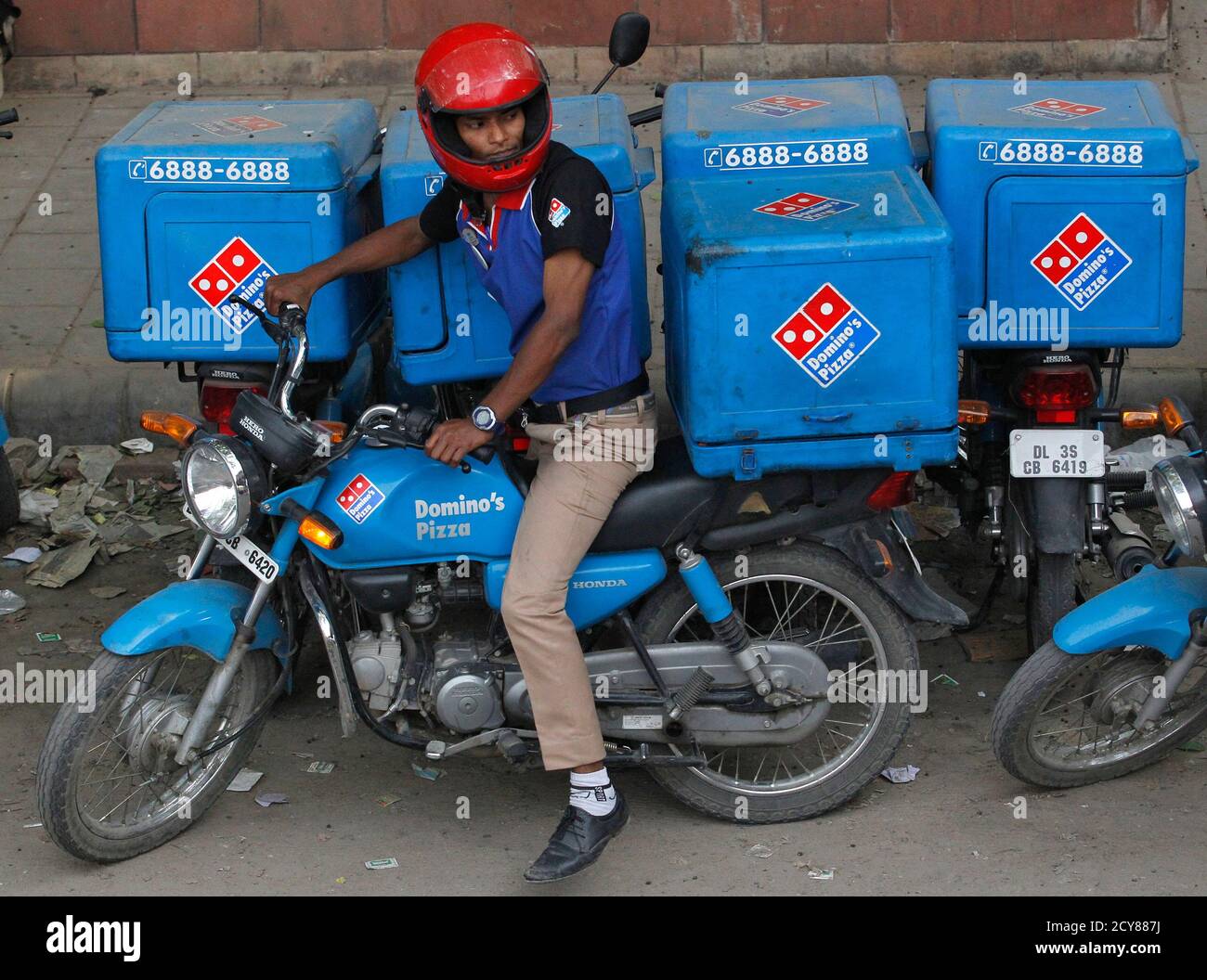 An employee rides a motorcycle to deliver Domino's Pizza to its customers  in New Delhi May 14, 2013. Global companies betting on India's potential as  a consumer market are looking beyond the