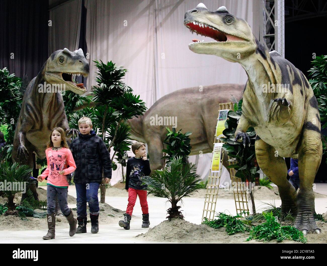 Children walk by life-sized Ceratosaurus dinosaur models in Vienna February 7, 2014. The travelling exhibition "World of Dinosaurs" shows some 50 life-sized dinosaur models and runs in Vienna until February 23. REUTERS/Heinz-Peter Bader (AUSTRIA - Tags: SCIENCE TECHNOLOGY SOCIETY) Banque D'Images