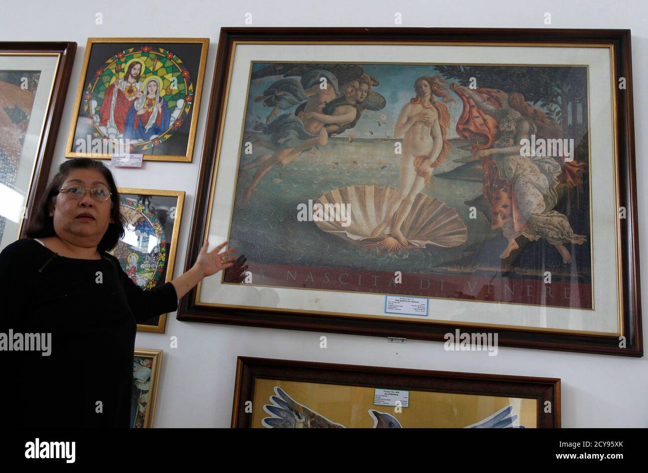 Filipino businesswoman Gina Lacuna shows her collection of jigsaw puzzle  boxes as she stands in front of an 18,000-piece jigsaw puzzle of Retablo De  Santa Columba, which took her 1095 hours to