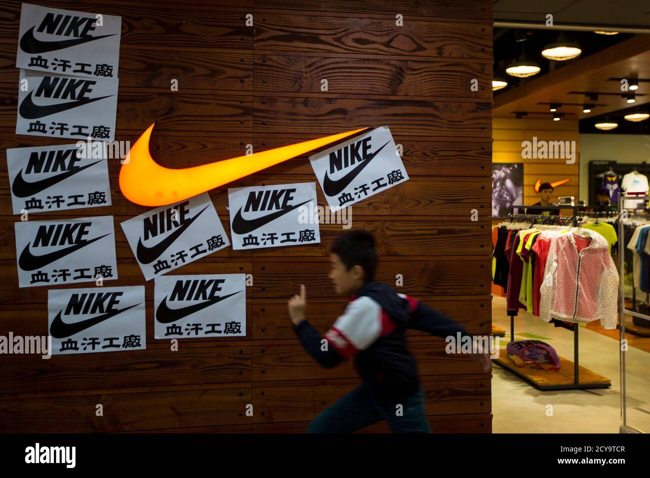 A child runs past protest signs pasted around a Nike logo in support of the  strike by workers of Yue Yuen Industrial Holdings in Dongguan, during an  International Labour Day rally in