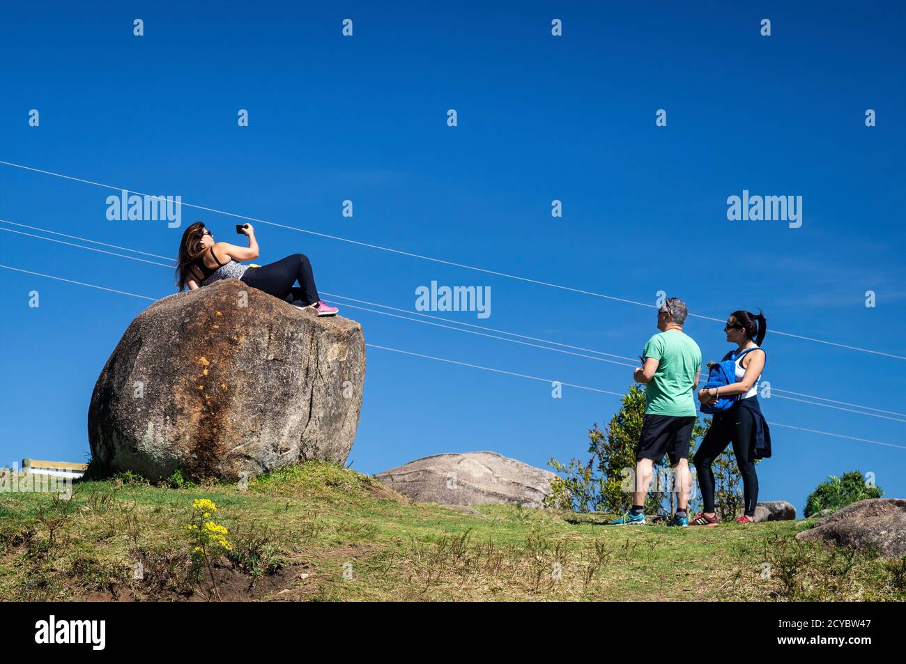 Un couple regardant l'un de ses collègues prenant des selfies sur une grande pierre à proximité Pedra da Macela, dans le parc national de Serra da Bocaina. Banque D'Images