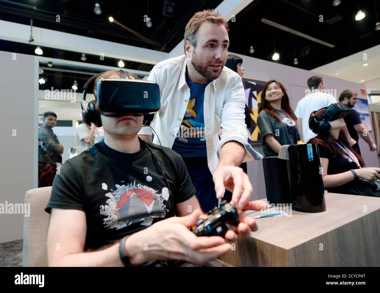 Paul Bettner, co-founder of Playful Corp which created the new "Lucky's  Tale" game for Oculus Rift, helps an attendee try the Oculus VR Inc. Rift  Development Kit 2 (DK2) headset at the