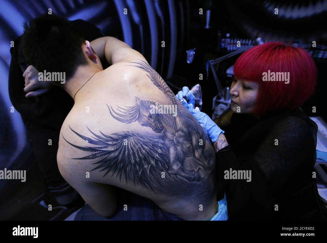 Tattoo artist Sun Lan tattoos the image of a horse with wings on the back  of her client Li Sheng at her studio ahead of the upcoming Chinese lunar  New Year in