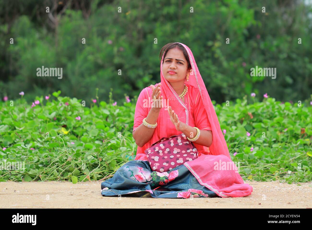 Portrait en gros plan d'une jeune indienne élégante et tendance blonde maquilleuse femme assis dans le jardin, secouer sa main et nettoyer la poussière Banque D'Images
