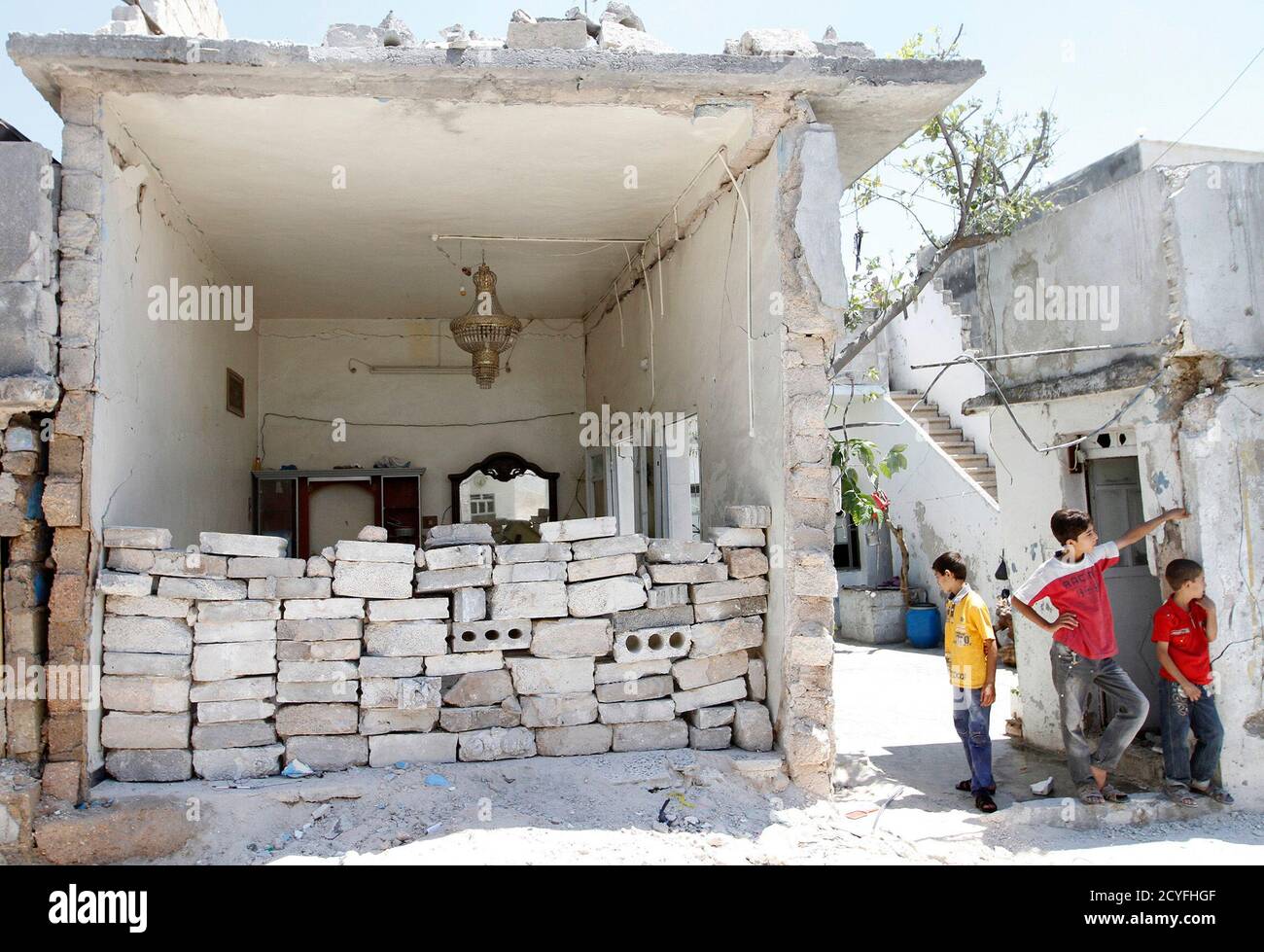 Boys stand near a damaged house in Azaz, near Aleppo, August 6, 2013. Syrian rebels captured a main military airport near the border with Turkey on Tuesday, consolidating their hold on a key supply route north of the city of Aleppo, opposition activists said. The reported capture of the Minnig Military Airport, situated on the road between Aleppo and the Turkish city of Gaziantep, after an eight-month siege, marks an important symbolic victory for the opposition, following a string of defeats to President Bashar al-Assad's forces in central Syria, the sources said. REUTERS/Hamid Khatib (SYRI Banque D'Images