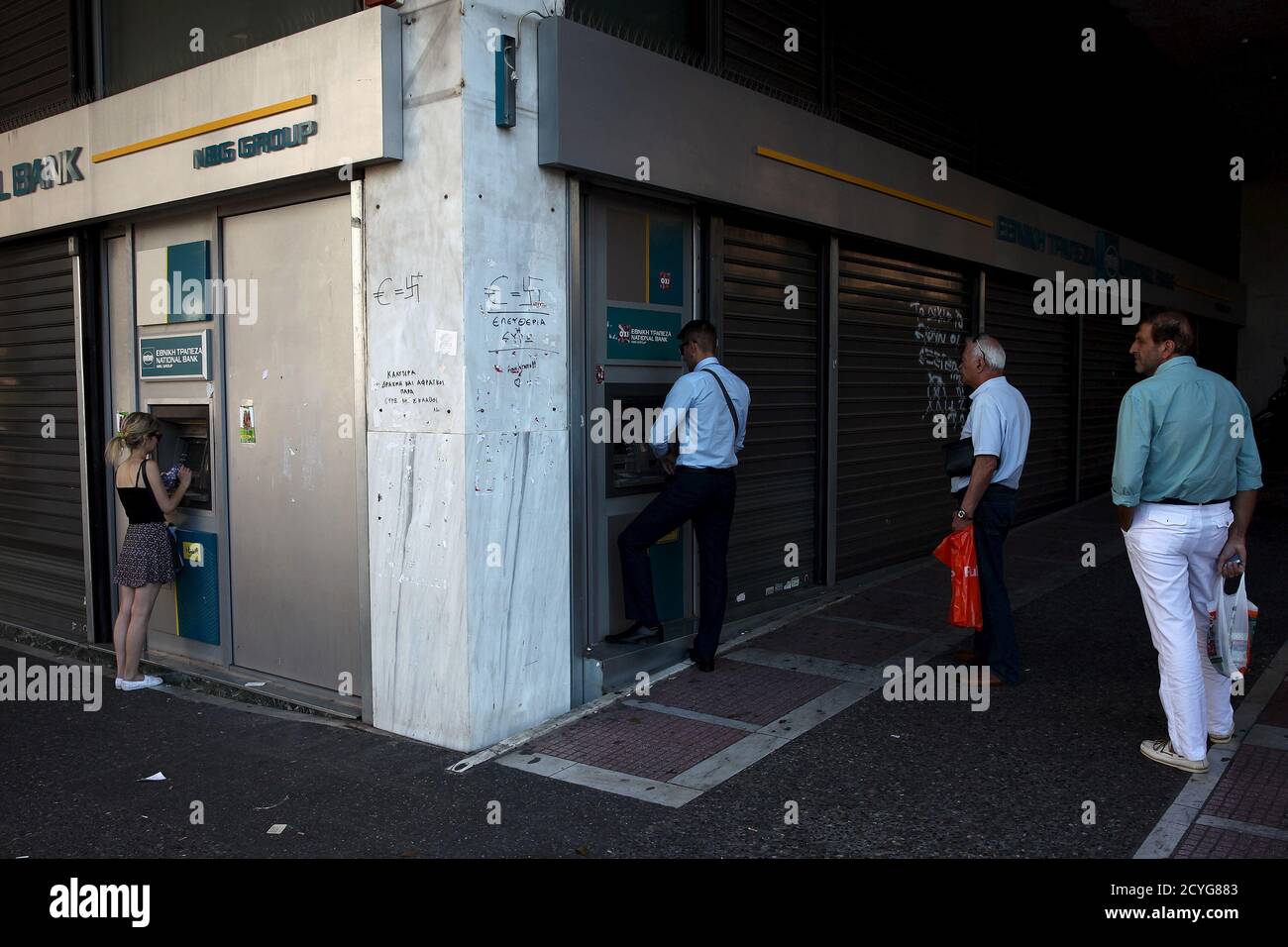 Les gens font la queue pour retirer de l'argent d'un guichet automatique (ATM) à l'extérieur d'une succursale de la Banque nationale à Athènes, Grèce le 17 juillet 2015. Un haut fonctionnaire grec a confirmé jeudi que les banques rouvriraient lundi et a déclaré que le gouvernement cherchait à permettre aux gens de procéder à des retraits de 60 euros sur plusieurs jours. REUTERS/Yiannis Kourtoglou Banque D'Images