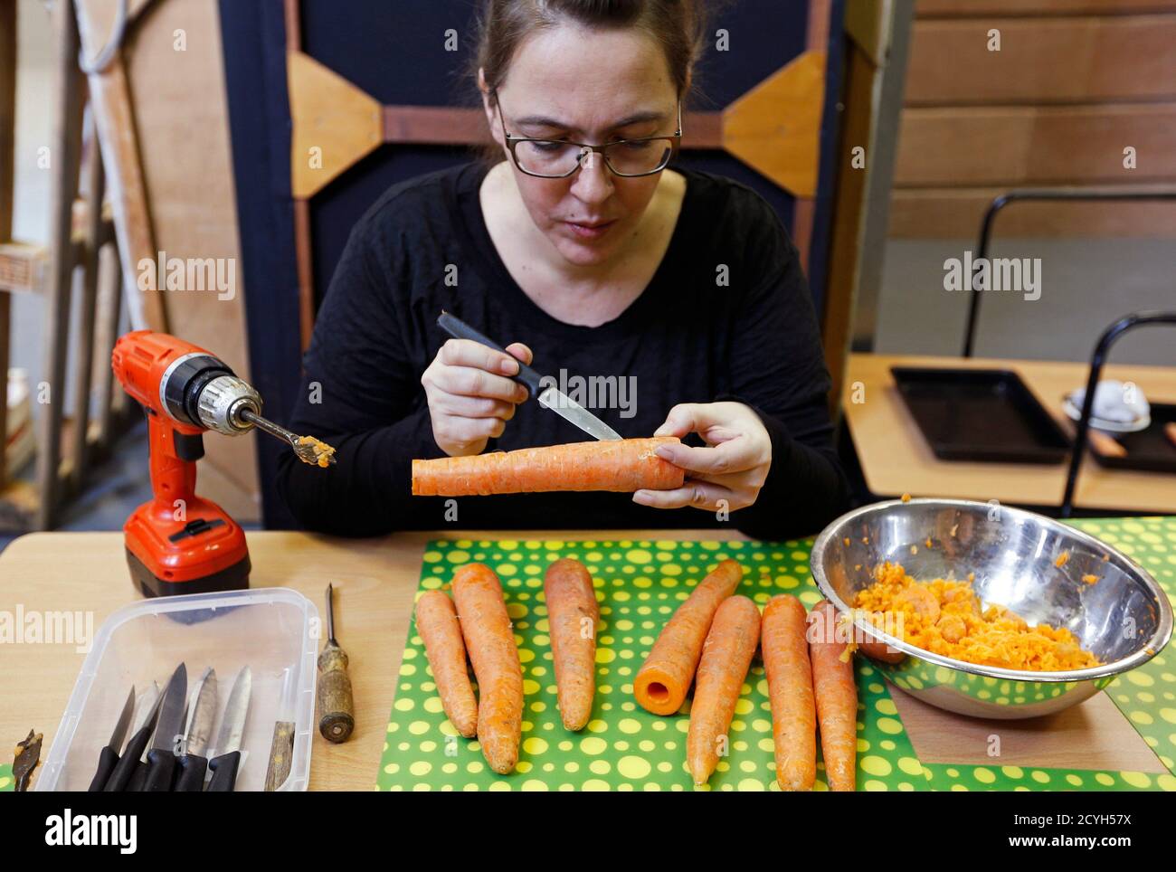 Austrian musician Barbara Kaiser, who is a member of the Vegetable  Orchestra, makes a musical instrument from a carrot during the preparations  for a concert in Haguenau, eastern France January 15, 2014.