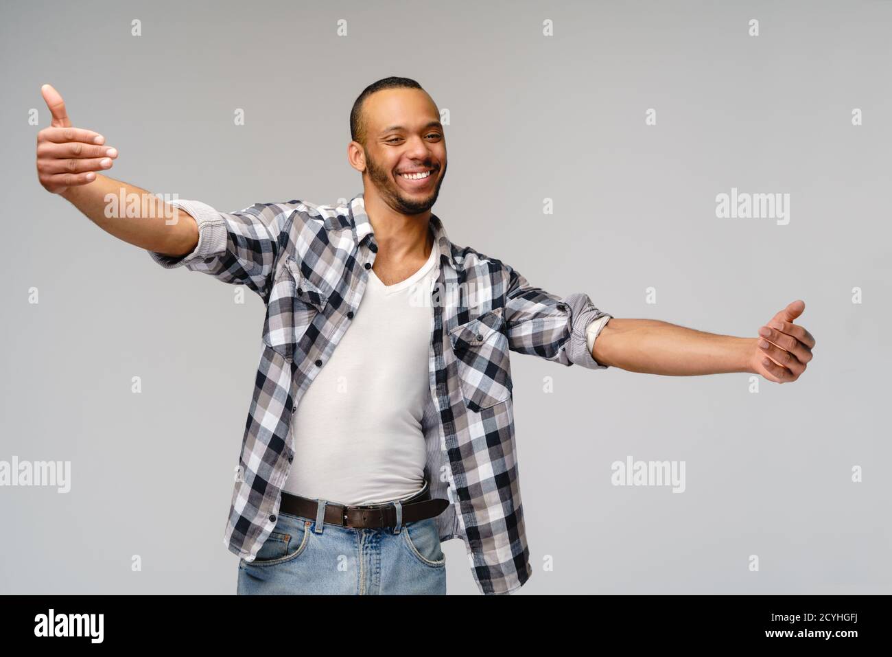 Sympathique homme afro-américain portant un t-shirt avec un sourire crasseux montrant des câlins geste sur fond gris Banque D'Images