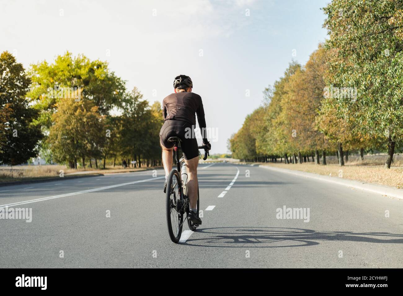 Homme sur un vélo de gravier sur la route, vue arrière. Cycliste bien équipé, qui fait du vélo moderne à l'extérieur Banque D'Images