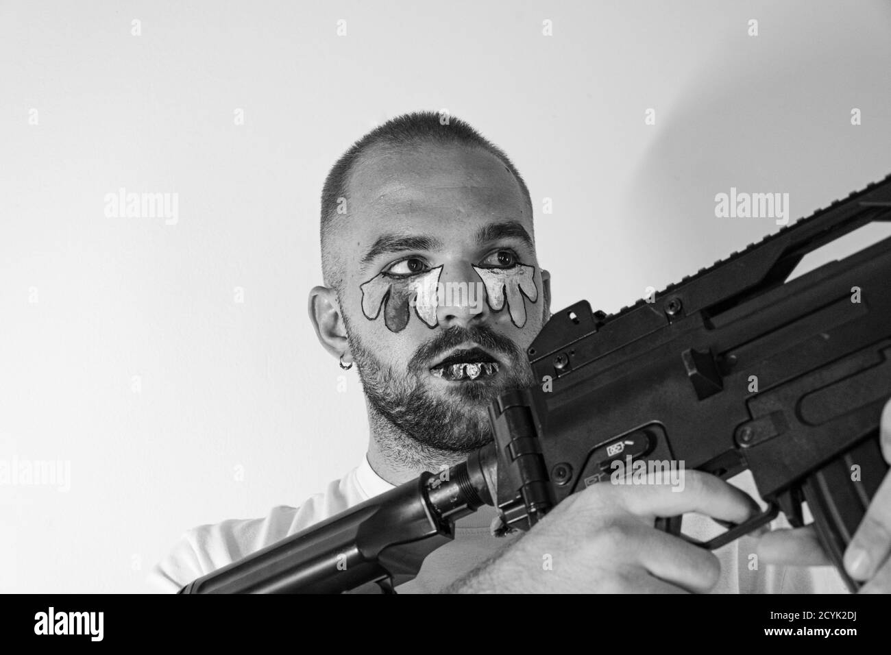 Un homosexuel avec une goutte d'eau peinte tenant un pistolet - le concept de discrimination LGBT Banque D'Images