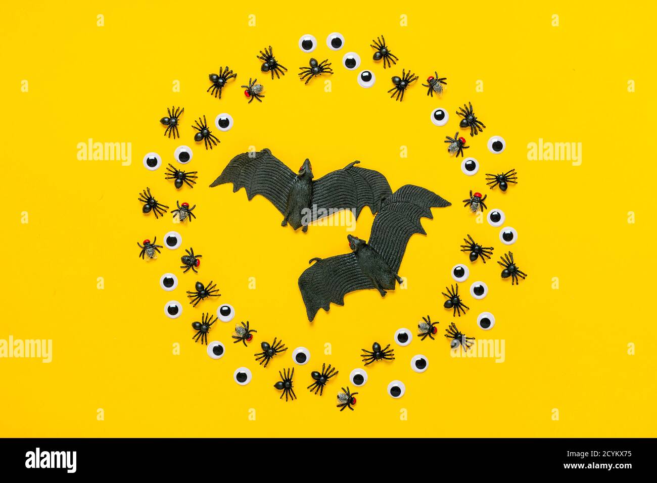 Cadre rond d'araignées et de mouches noires, yeux et chauve-souris à l'intérieur sur fond jaune vue du dessus Flat Lay Happy Halloween Creative concept Holiday Banque D'Images