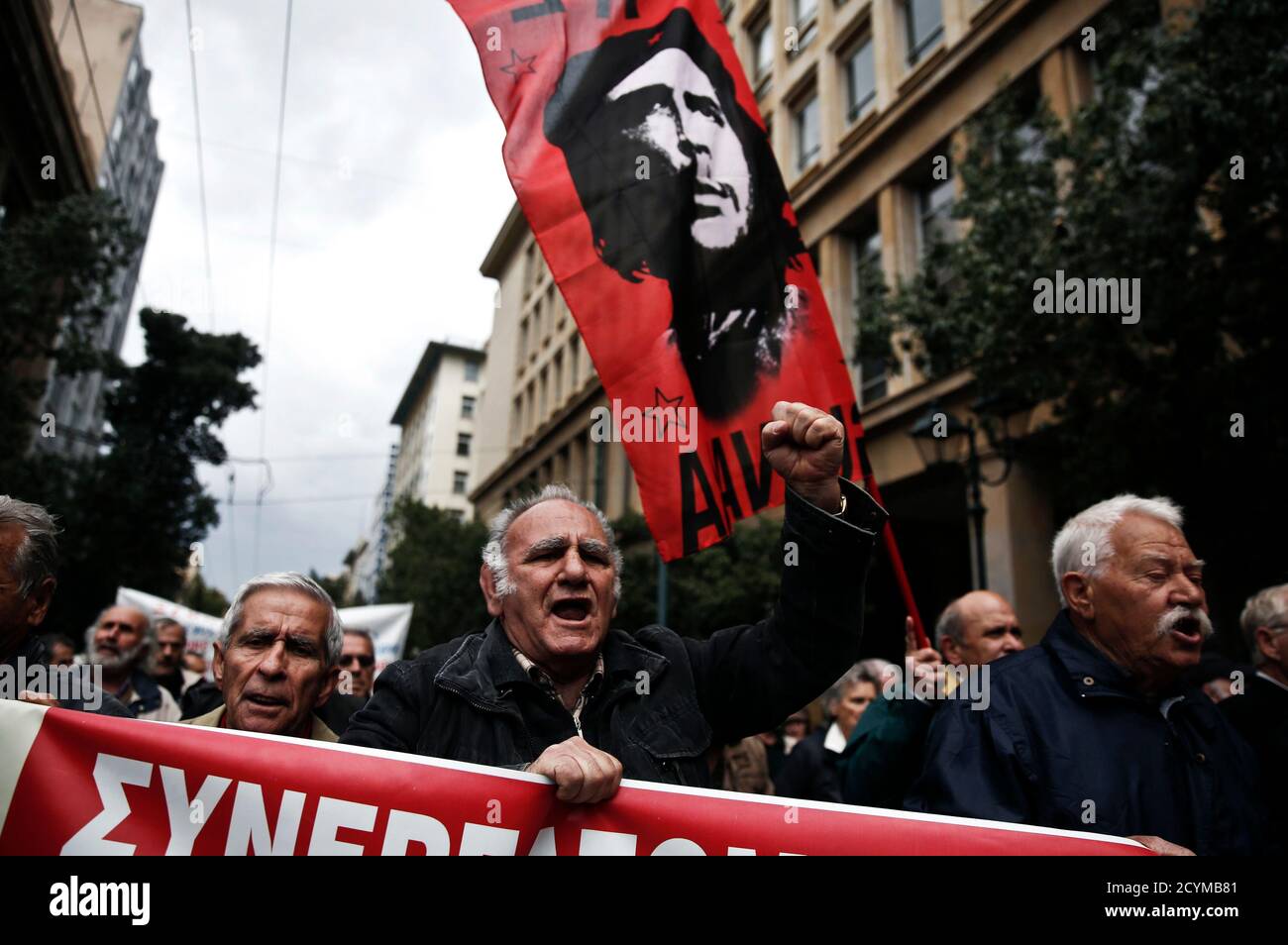 Pensioners march holding a banner and flag bearing an image of Cuban  revolutionary leader Che Guevara, during an anti-austerity rally in Athens  April 19, 2013. Greeks have lost almost a third of