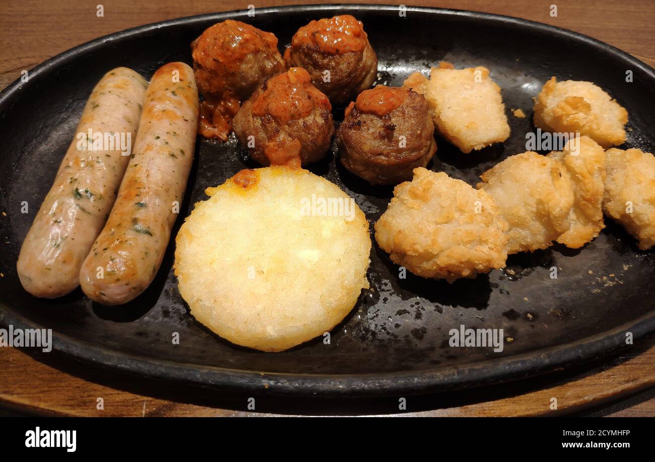 différents en-cas frais sur l'assiette noire, comme des boulettes de viande, des poulets frits, des saucisses, des crêpes aux pommes de terre Banque D'Images