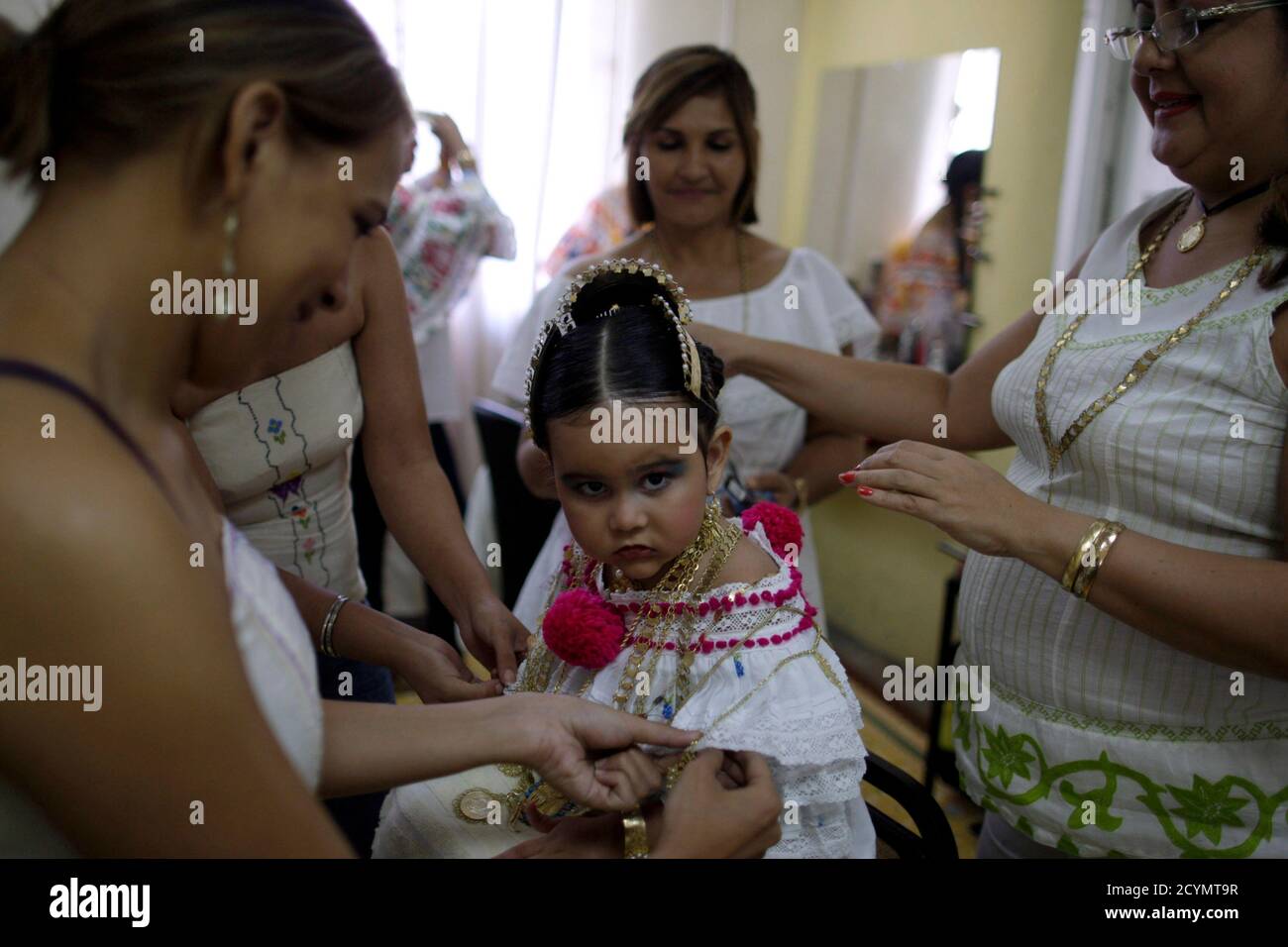 A girl is seen wearing traditional clothing known as "Pollera" inside a  beauty salon as she is helped by women before the annual Thousand Polleras  parade in Las Tablas, in the province