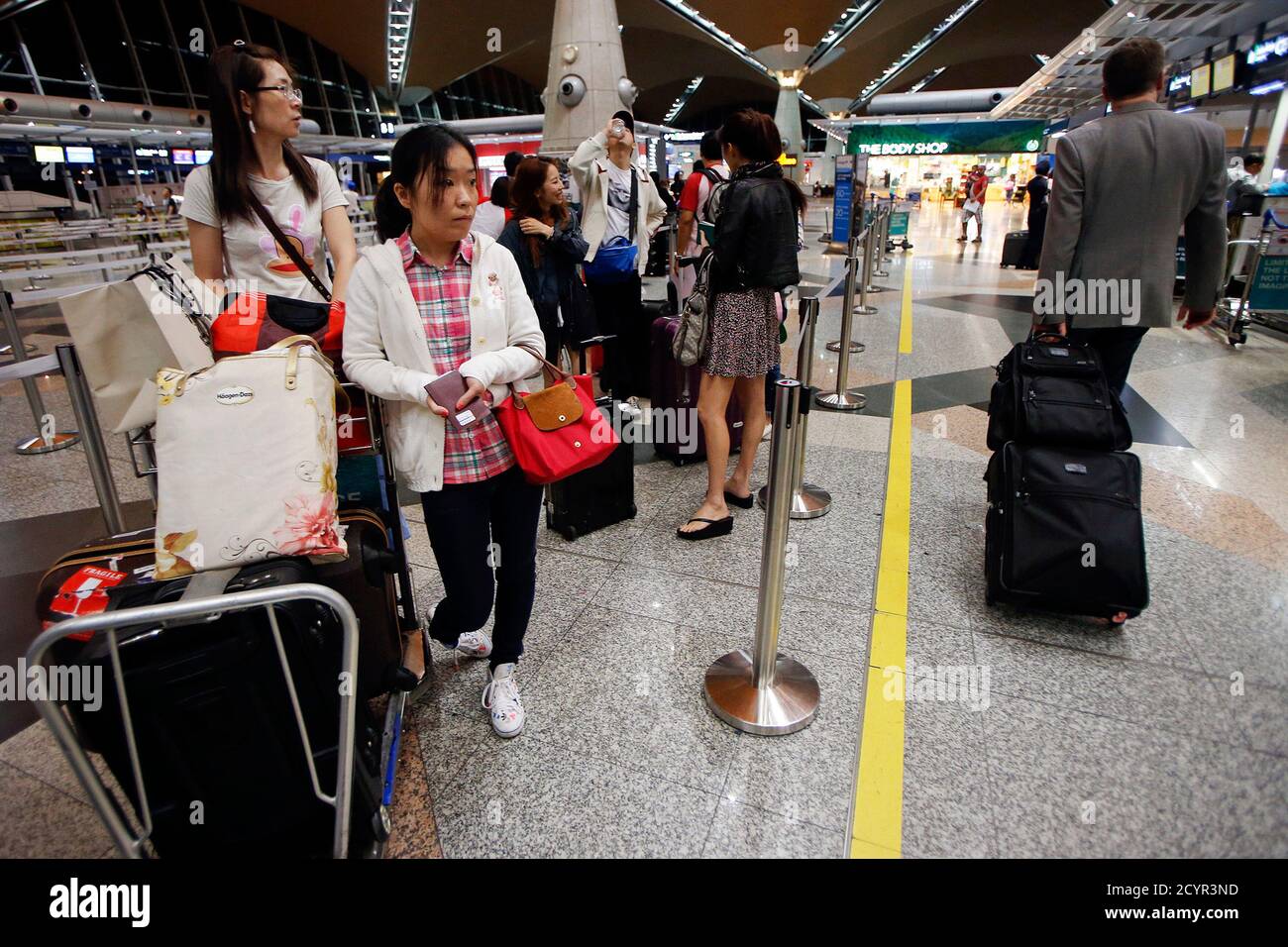 Passengers for Malaysia Airlines flight MH318 wait at the check-in counters  at Kuala Lumpur International Airport at approximately 10:45pm March 16,  2014. Malaysia Airlines flight number MH318 replaces the flight number of