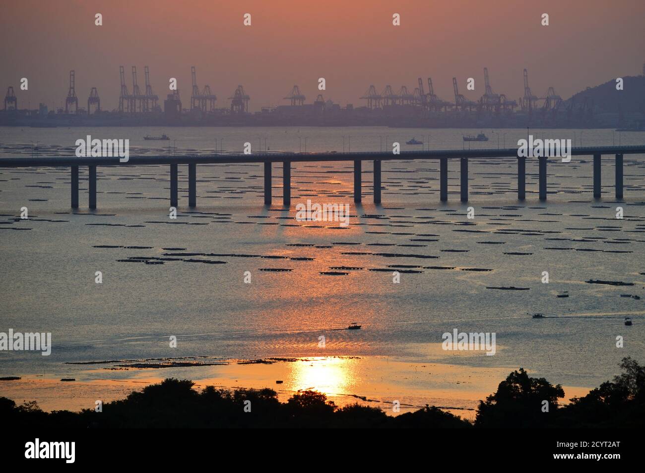 Pont de la baie de Shenzhen traversant Deep Bay, entre Hong Kong et Shenzhen, en Chine, au coucher du soleil avec les terminaux à conteneurs Shekou en arrière-plan Banque D'Images