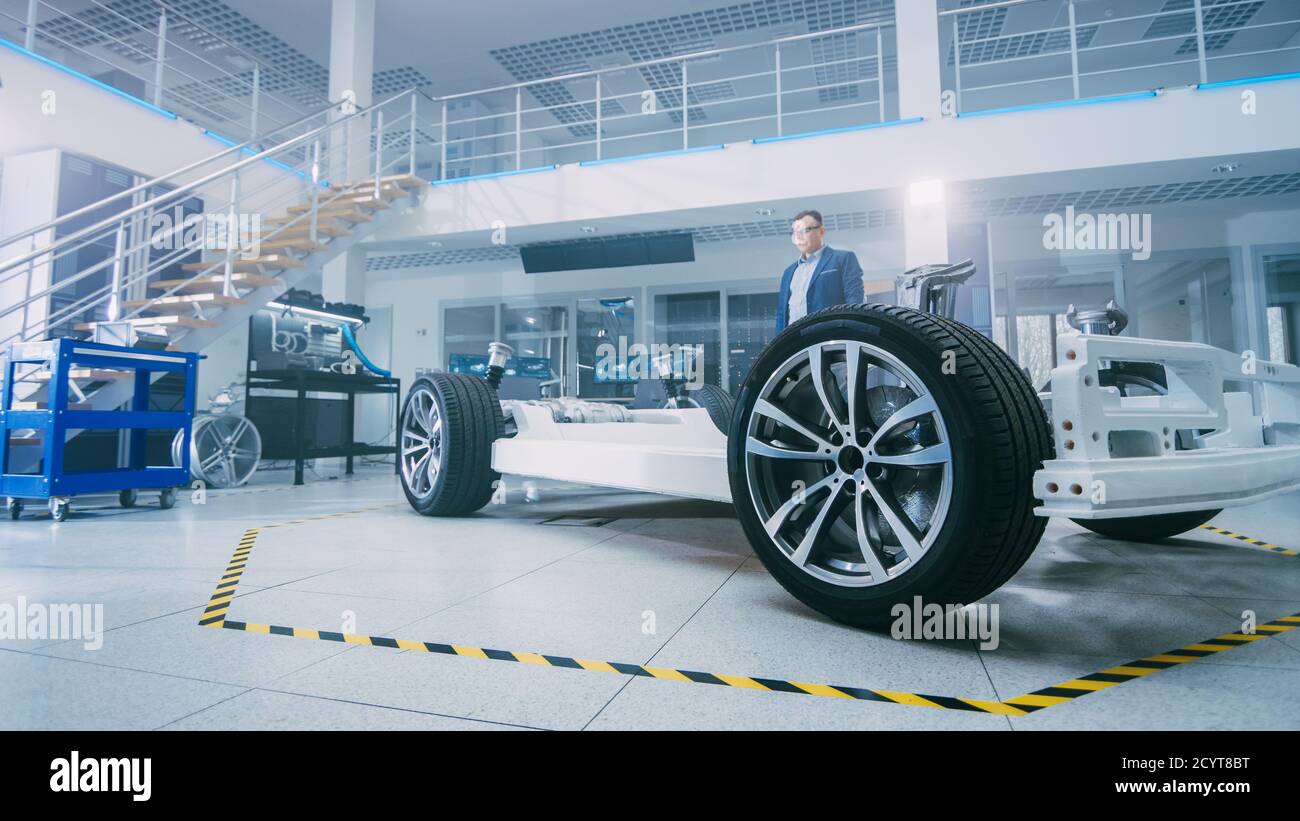 Ingénieur en conception automobile qui étudie le prototype de châssis de voiture électrique. Dans le concept d'installation de laboratoire d'innovation cadre de véhicule comprend des roues, moteur Banque D'Images