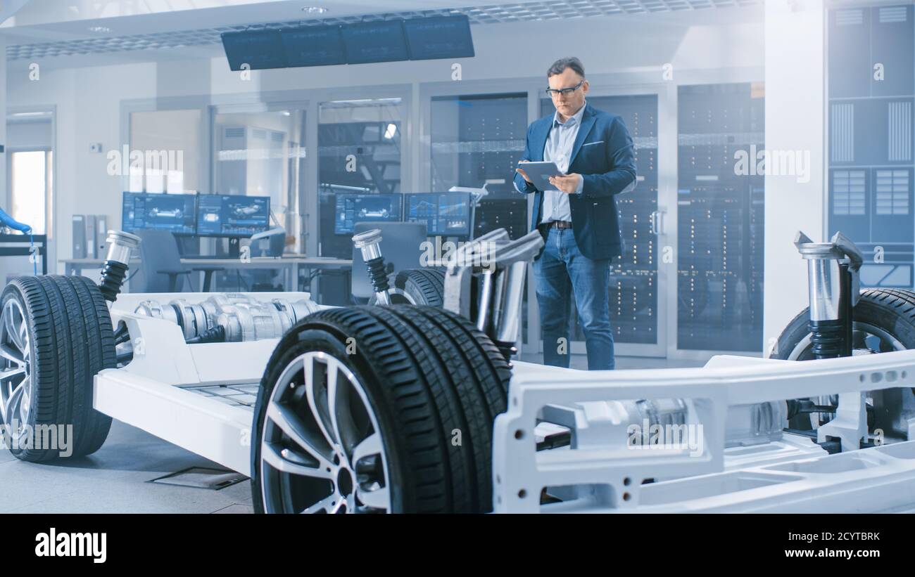 Ingénieur concepteur automobile regardant le dessin technique d'un prototype de châssis de voiture électrique sur une tablette. Dans le concept d'installation de laboratoire d'innovation Banque D'Images
